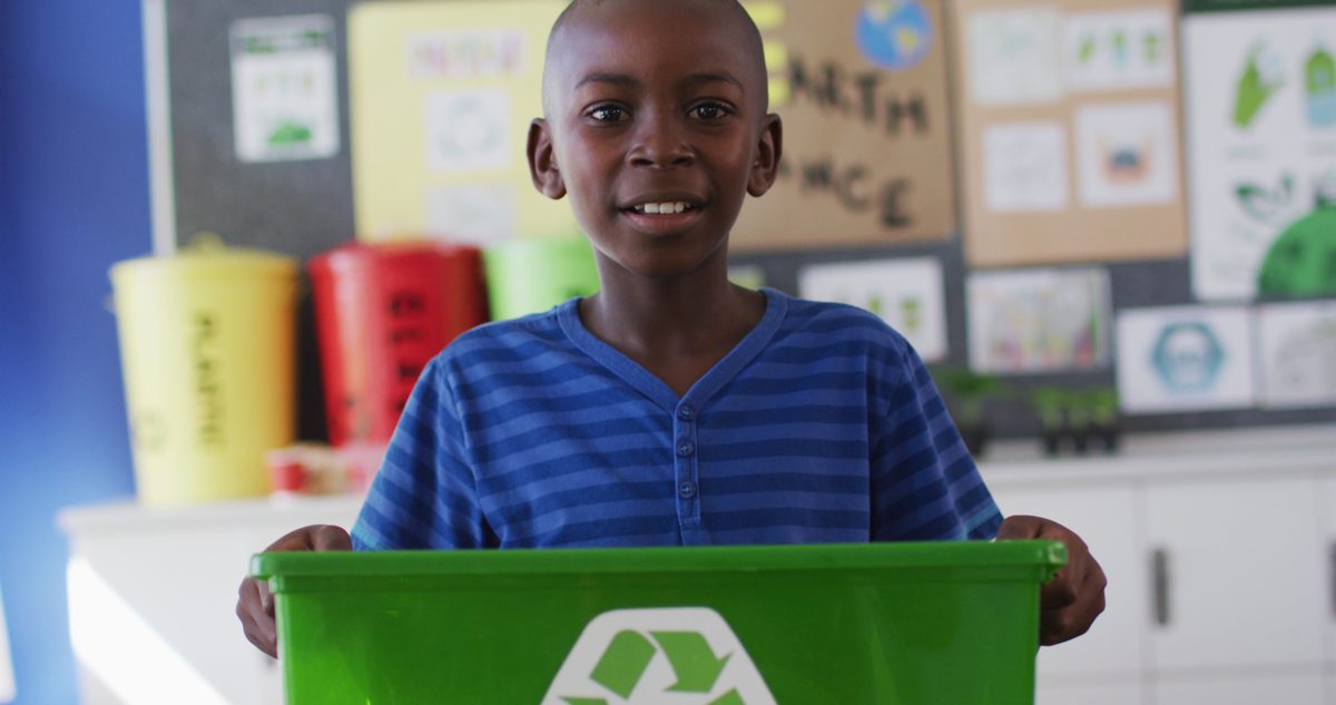 Elementary student holding a classroom recycling bin