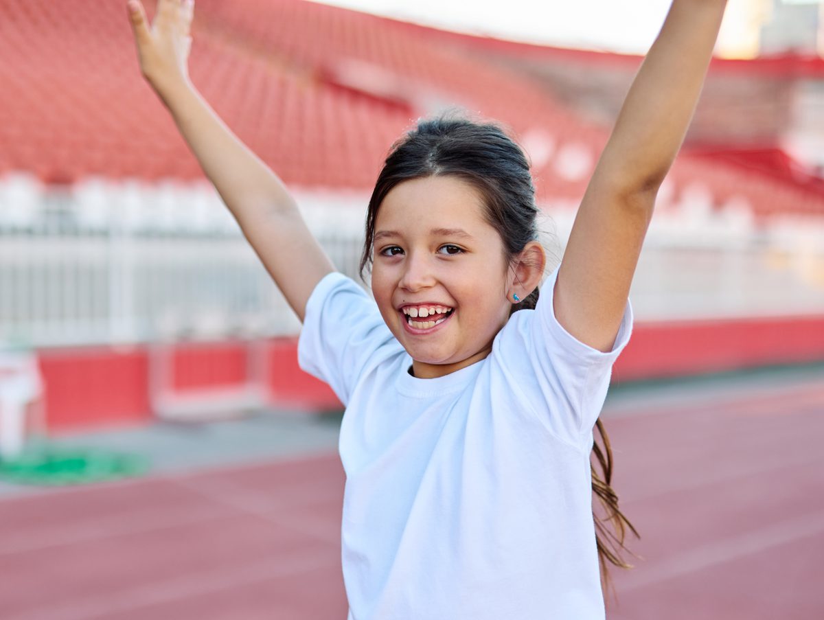Young student cheering with arms raised at a track stadium