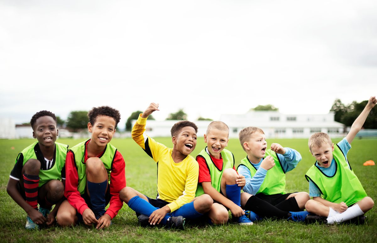 A diverse group of kids on a youth soccer team cheering together