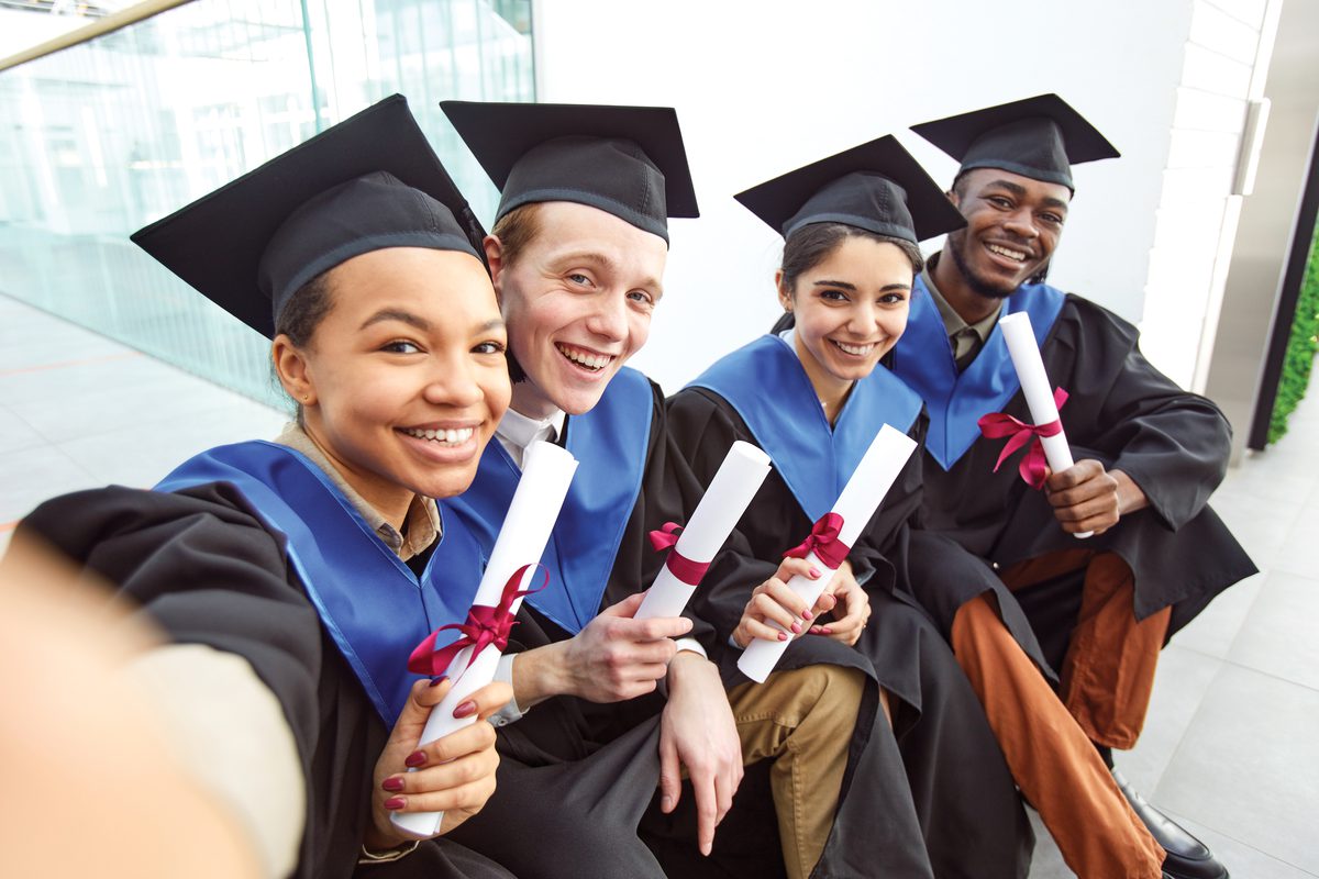 A diverse group of graduates celebrating with their diplomas